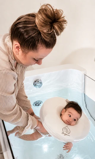 Eine Mutter begleitet ihr Baby beim Floating im Babyboom Babyspa
