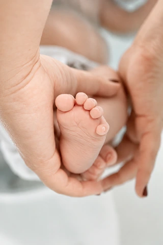 Eine Hand hält einen Babyfuß im Wasser