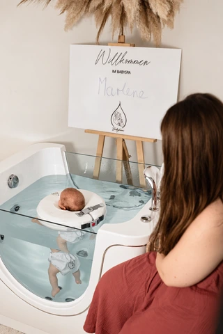 Eine Mutter sitzt bei ihrem Baby an der Floating-Wanne