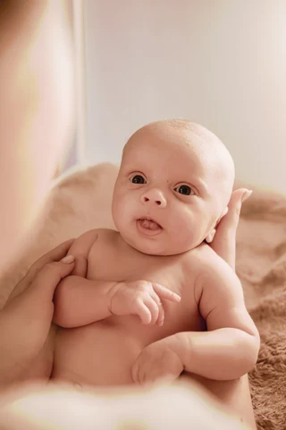 Eine Bezugsperson hält ihr aufmerksames Baby