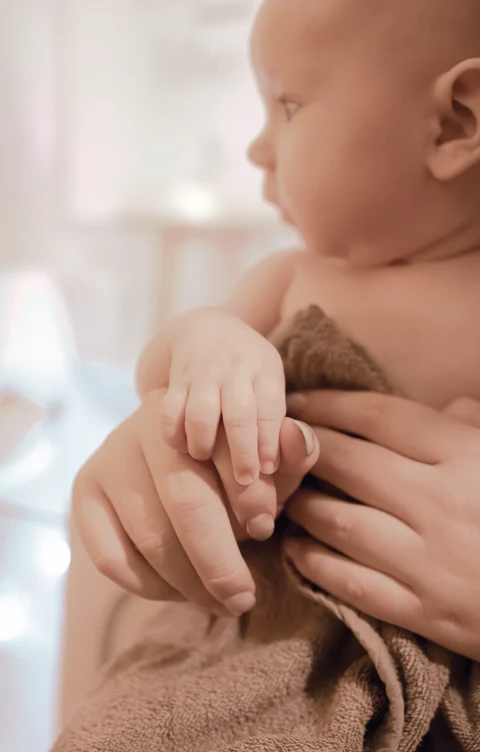 Die kleine Hand eines Babys hält einen Finger seiner Bezugsperson