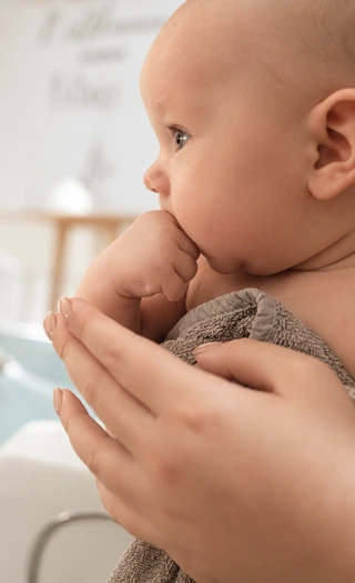 Ein Baby wird behutsam gehalten und schaut zur Seite