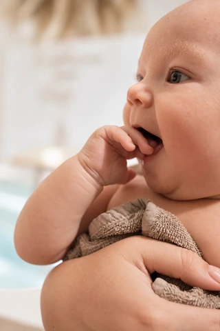 Ein Baby entdeckt seine Hand, während es gehalten wird