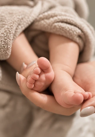 Kleine Babyfüße liegen in den Händen einer Bezugsperson
