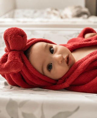 Ein Baby liegt eingekuschelt in einem roten Bademantel
