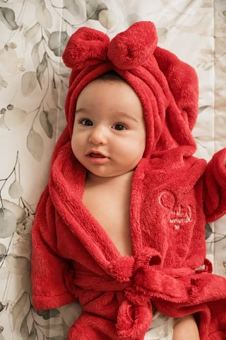 Ein Baby liegt eingekuschelt in einem roten Bademantel