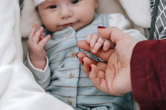 Baby hält die Hand einer erwachsenen Bezugsperson