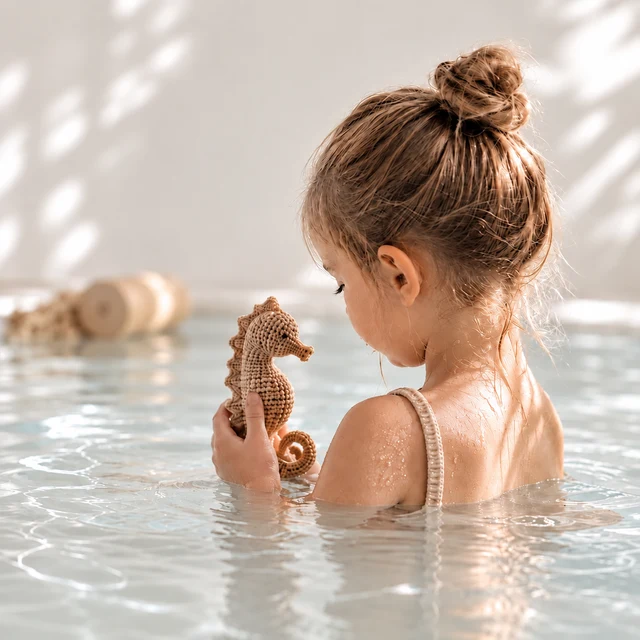 Kind mit einem gehäkelten Seepferdchen im Hallenbad